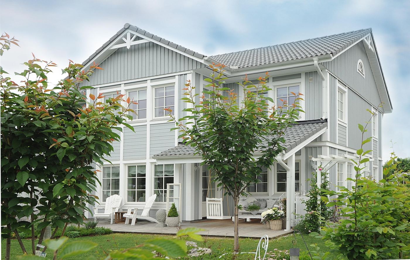 Ljusgrå villa med trädgård och altan